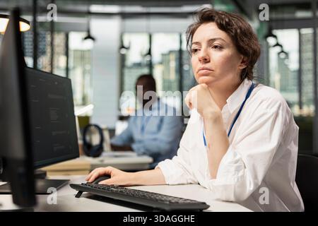 Female programmer using AI LLM chatbot, optimizing company systems performance. Woman in startup office uses artificial intelligence assistant to convert manual workflows into automated scripts Stock Photo