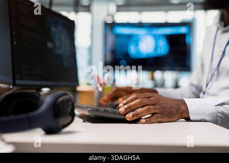 Close up of technician in office typing on keyboard, running AI automation scripts to reduce repetitive coding tasks. Worker writing code, using artificial intelligence technology on PC Stock Photo