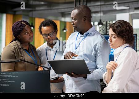 Team of programmers developing software applications, designing coding solutions together. Coworkers conducting detailed code review, optimizing performance, analyzing technical issues Stock Photo