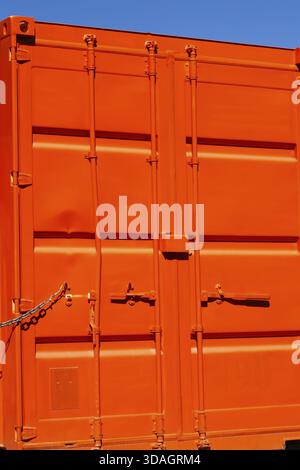 Locked bright fluorescent orange painted metal box shaped shipping container with doors locked shut, Quebec, Canada Stock Photo