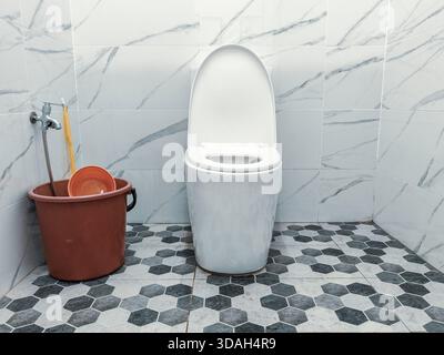 Modern White Toilet and Closed Seat in Stylish Bathroom with Marble Look Wall and Hexagonal Floor Tiles Stock Photo
