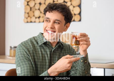 Young man with Turkish tea in kitchen Stock Photo