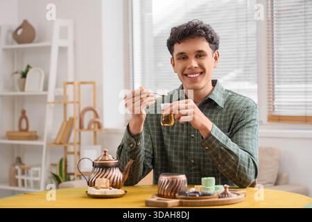 Young man with Turkish tea at table in kitchen Stock Photo