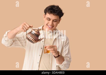 Young man with Turkish tea and teapot on beige background Stock Photo