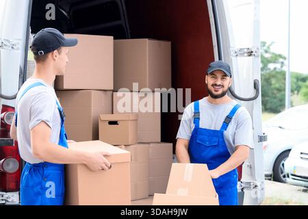Male movers unloading boxes from car outdoors Stock Photo