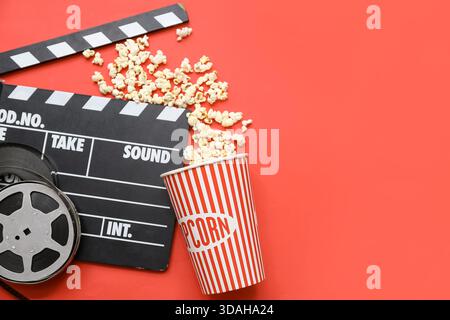 Movie clapper with film reels and popcorn on red background Stock Photo
