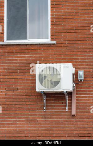 Canada, Quebec, 27 November 2025 : White air conditioning unit mounted on brick wall under window Stock Photo