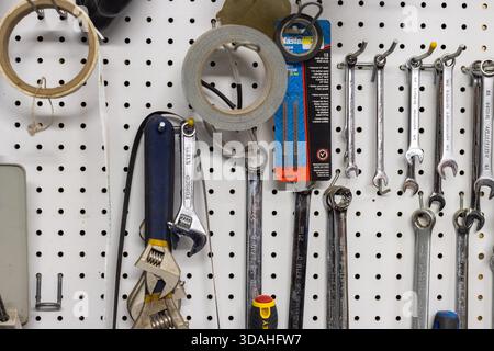 Canada, Quebec, 17 November 2025 : Wrenches, screwdrivers, tape, and saw blades hanging on toolboard Stock Photo