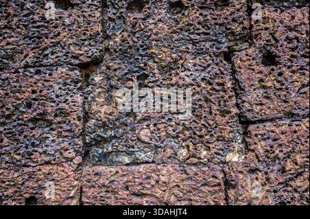 Red laterite stone texture porous surface close up ancient wall background rough material geology pattern architecture detail historic grunge abstract Stock Photo