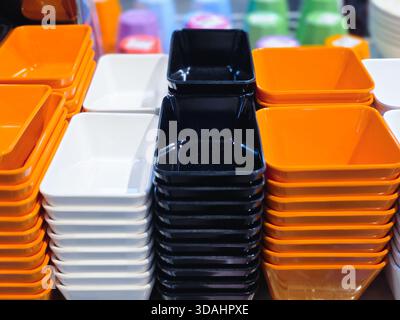 Colorful stack of square plastic bowl and container arranged in neat row. vibrant orange, white, and black plasticware create geometric pattern on dis Stock Photo