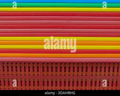 Vibrant, colorful abstract background showing striped pattern. red stack of plastic objects creates unique texture, cheerful and bright geometric desi Stock Photo