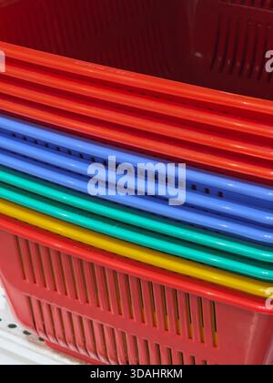 Colorful stack of plastic shopping basket creates vibrant abstract pattern. This cheerful retail background shows detail, order, and repetition for cl Stock Photo