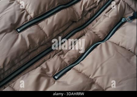 Close-up image showing the detail of a black zipper pull on beige canvas fabric Stock Photo