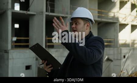 Focused engineer in hard hat discussing project plans on a sunny day Stock Photo
