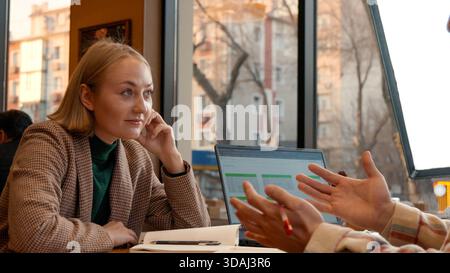 Woman in a cafe talking to a man, gesturing with her hand for emphasis Stock Photo