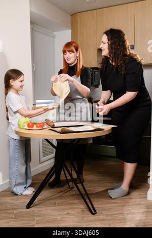 Family is making homemade pizza. Woman and daughter create and enjoy homemade pizza recipes, happily cooking together in comfort of their own home Stock Photo