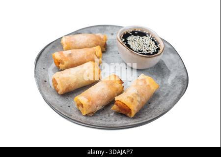 Crispy fried spring rolls served on ceramic plate with soy dipping sauce and sesame seeds on white background. Stock Photo