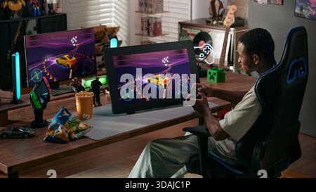 Young gamer playing racing video game on large graphics tablet screen using controller in gaming setup Stock Photo