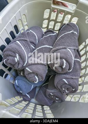 Satisfying pile of clean gray rolled towels with striped pattern in laundry basket. neatly organized result of housework and finished chore, fresh and Stock Photo