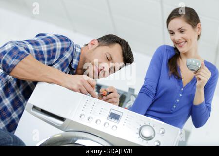 woman looking at repairman repairing dishwasher in kitchen Stock Photo