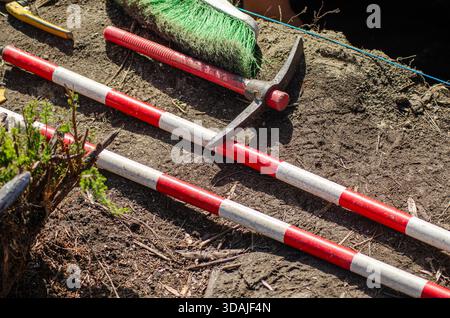 Red Striped Measuring Sticks And Pickaxe Work Site Soil Stock Photo