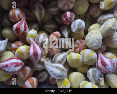 Colorful background of sweet striped candy. Delicious traditional sugar dessert food in pile. Many multicolored hard candies with red, yellow and whit Stock Photo