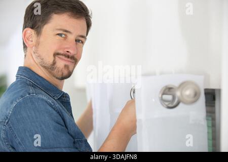 handyman services - worker installing window curtain rod Stock Photo