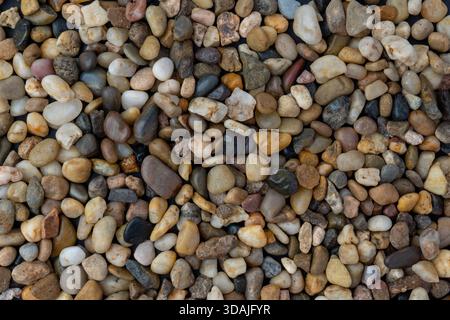 Close-up, full-frame texture shot of naturally varied, small, smooth river stones and pebbles in various colors Stock Photo