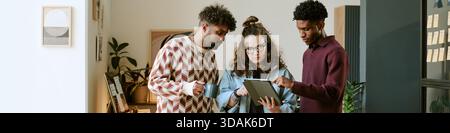 Multiethnic Young Adults Collaborating on Digital Tablet in Modern Office Stock Photo