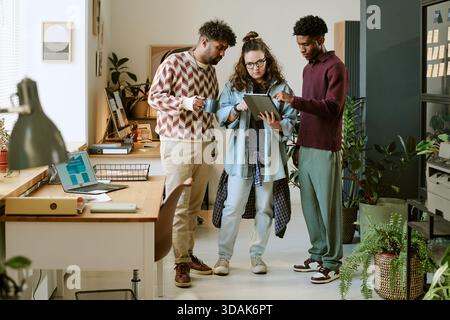 Young Multiethnic Colleagues Collaborating on Digital Tablet in Modern Office Stock Photo