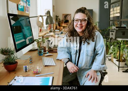 Portrait of Young Adult Caucasian Woman Smiling While Working at Desk Stock Photo