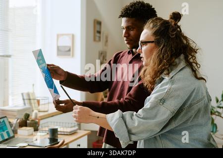 Young Caucasian Woman and Young Black Man Collaborating on Project Indoors Stock Photo