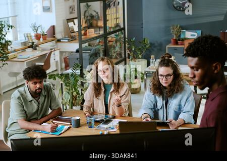 Diverse Young Adults Collaborating during Creative Meeting in Modern Office Stock Photo