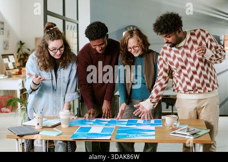 Diverse Young Adults Collaborating on Creative Project in Modern Office Setting Stock Photo