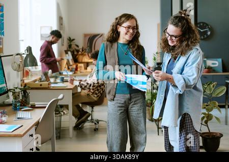 Two Young Adult Caucasian Women Collaborating on Project in Modern Office Stock Photo