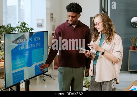 Young Caucasian Woman and Young Black Man Discussing Real Estate Presentation Stock Photo