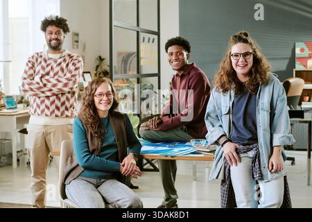 Diverse Young Adults Smiling and Collaborating in Modern Office Workspace Stock Photo