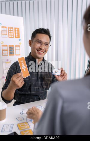 A group of UX/UI designers brainstorming creative ideas together, discussing color palettes and layout concepts for a new mobile application interface Stock Photo