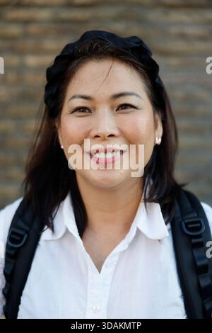 Smiling woman against textured brick wall, Stock Photo
