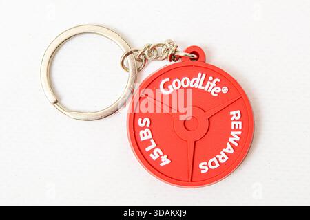 Red GoodLife keychain shaped like a weight plate on a white background. Stock Photo