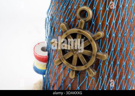 Portuguese souvenir detail, nautical decor featuring a ship wheel charm on blue fishing net. Stock Photo