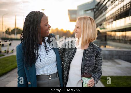 Diverse business women collaborating and smiling outdoors Stock Photo