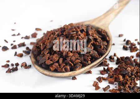 Spoon of crushed cacao nibs on white background Stock Photo