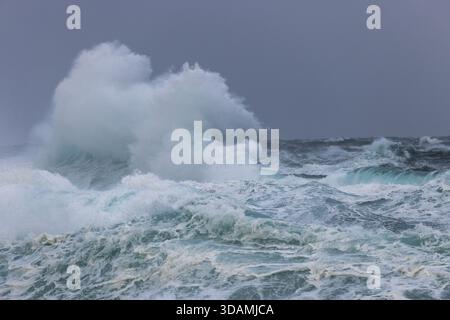 View of frothy, churning waves crash and collide under a moody, overcast sky, a powerful display of nature's raw energy, Sorvagur, Vagar, Faroe Island Stock Photo