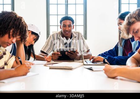 Multiethnic group of young students meeting at the library - multiethnic young students collaborating and studying with digital devices and notebooks Stock Photo