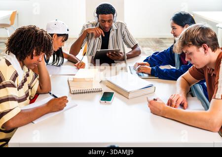 Multiethnic group of young students meeting at the library - group of young multiethnic students concentrating on their studies, working collaborative Stock Photo