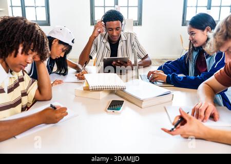 Multiethnic group of young students meeting at the library - multiethnic young students collaborating on their studies, using books, laptops, and tabl Stock Photo