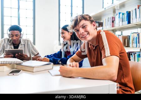 Multiethnic group of young students meeting at the library - diverse young students are sitting at a table in a bright library, focusing on their stud Stock Photo