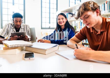 Multiethnic group of young students meeting at the library - multiethnic young students collaborating on university project in library, sharing knowle Stock Photo