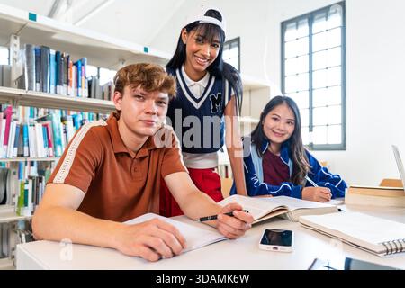 Multiethnic group of young students meeting at the library - young diverse students collaborating on academic work at a library table. Group learning, Stock Photo
